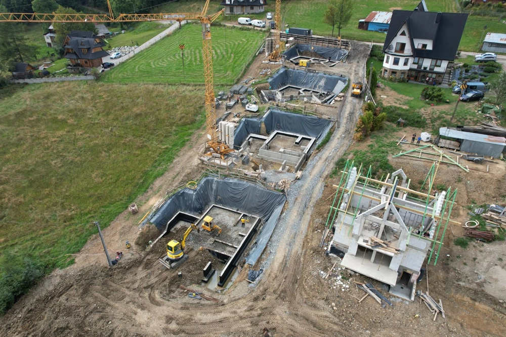 Fundamenty: wykopy z koparką i żurawiem pod domy jednorodzinne na górskim terenie budowy
