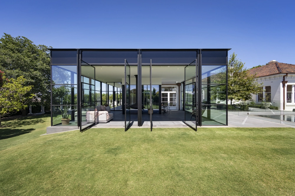 Ogrody zimowe z przeszklonymi ścianami i wyjściem na zadbany trawnik