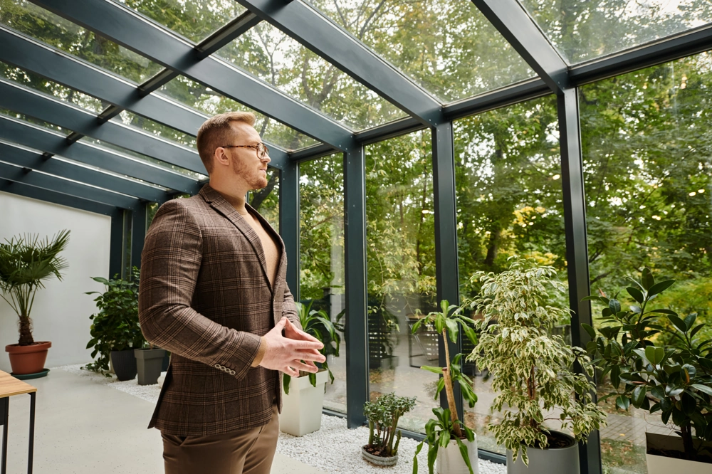Przestronny przeszklony ogród zimowy z mężczyzną oglądającym rośliny – Ogrody zimowe